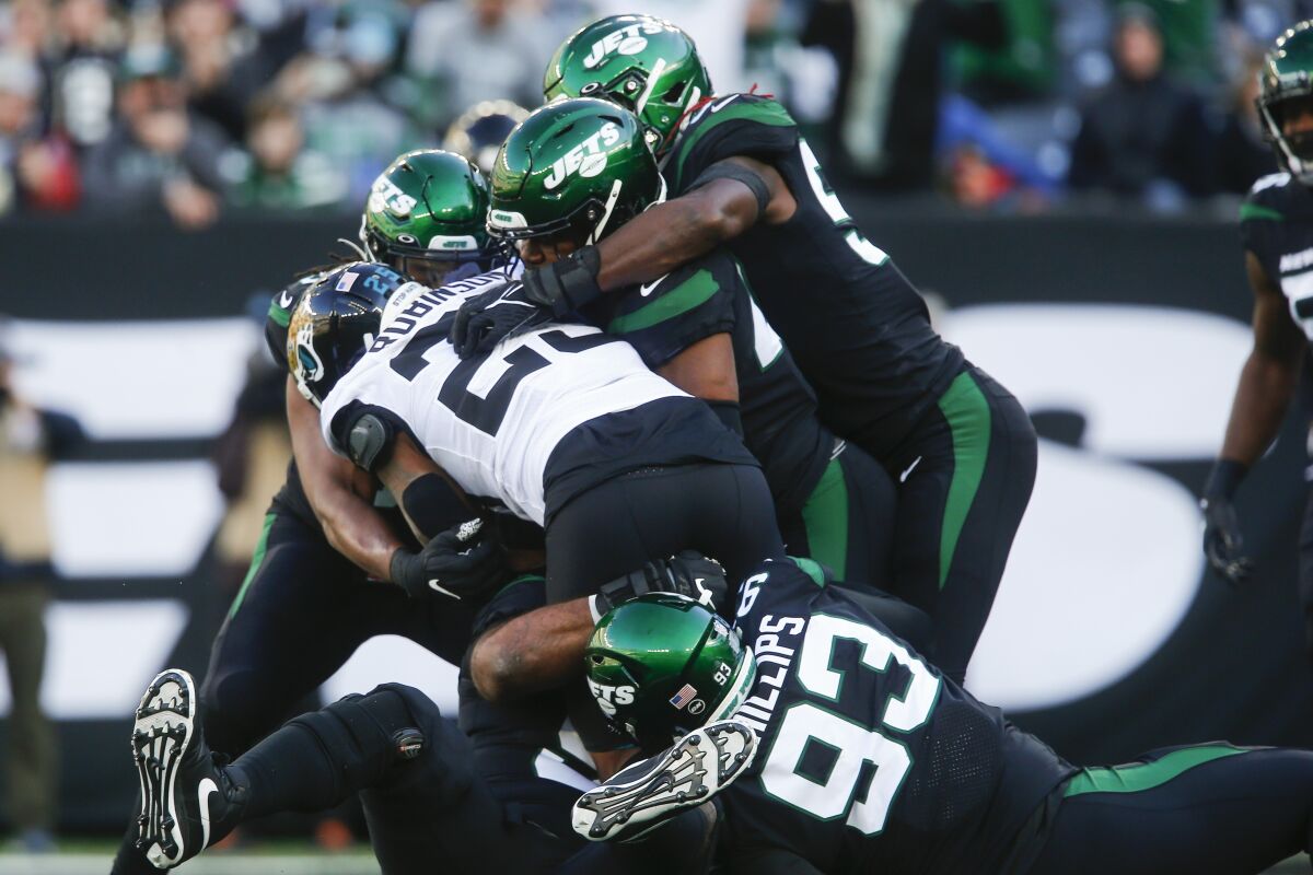 Jacksonville Jaguars running back James Robinson (25) is tackled by New York Jets' Kyle Phillips (93) and C.J. Mosley (57) during the first half of an NFL football game Sunday, Dec. 26, 2021, in East Rutherford, N.J. (AP Photo/John Munson)