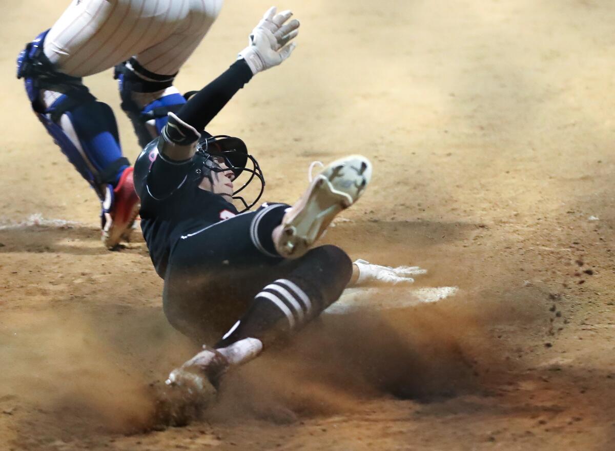 Huntington Beach's Cali Bennett slides into home plate after a hit and a three-base error against Los Alamitos on Tuesday.