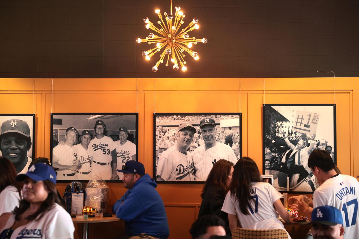 People sit at small, round tables in a paneled room with black-and-white photos of baseball players.