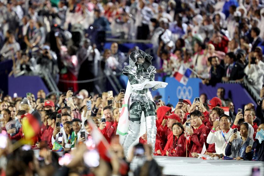 PARIS, FRANCE JULY 26, 2024 - Floriane Issert, a Gendarmerie non-commissioned officer of the National Gendarmerie, carries the Olympic flag in Paris, France, during the opening ceremony of the 2024 Summer Olympics, Friday, July 26, 2024. (Wally Skalij/Los Angeles Times)