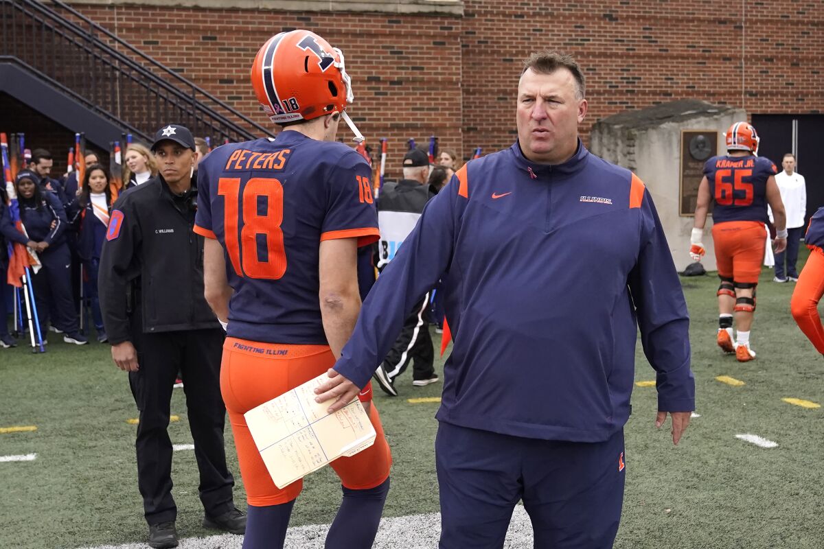 Illinois head coach Bret Bielema, right, watches his players walk off the field including quarterback Brandon Peters after the team's 20-14 loss to Rutgers in an NCAA college football game Saturday, Oct. 30, 2021, in Champaign, Ill. (AP Photo/Charles Rex Arbogast)