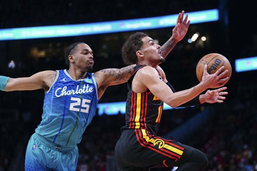 Atlanta Hawks guard Trae Young (11) drives to the basket past Charlotte Hornets forward P.J. Washington (25) during the first half of an NBA play-in basketball game Wednesday, April 13, 2022, in Atlanta. (AP Photo/John Bazemore)