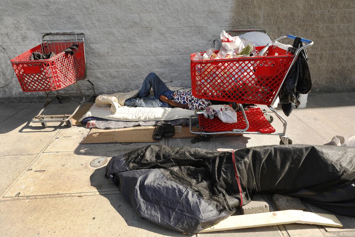 One week after Los Angeles Bureau of Sanitation crews cleaned up the homeless encampment of Rickey Harris, he lies on his bed at 41st Place and Alameda Street after returning with his three shopping carts of personal items.