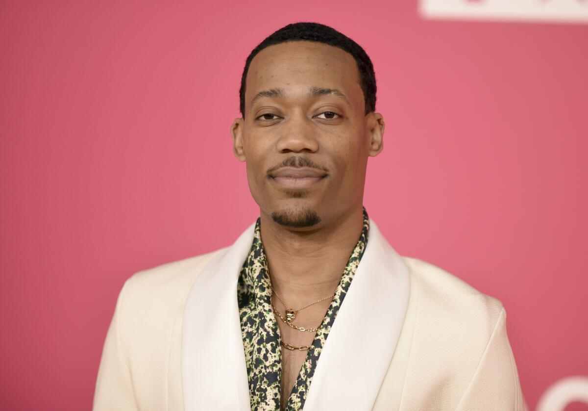 Actor Tyler James Williams in a white blazer against a pink backdrop