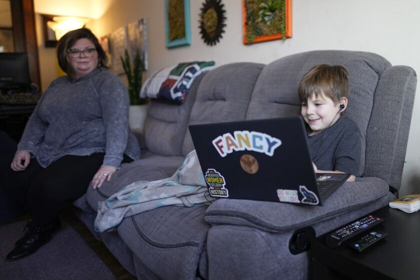 Jessica Blalack, izquierda, mira mientras su hijo Phoenix Blalack, de 6 años, trabaja con un tutor a distancia en su casa en Indianápolis, 7 de marzo de 2023. (AP Foto/AJ Mast)