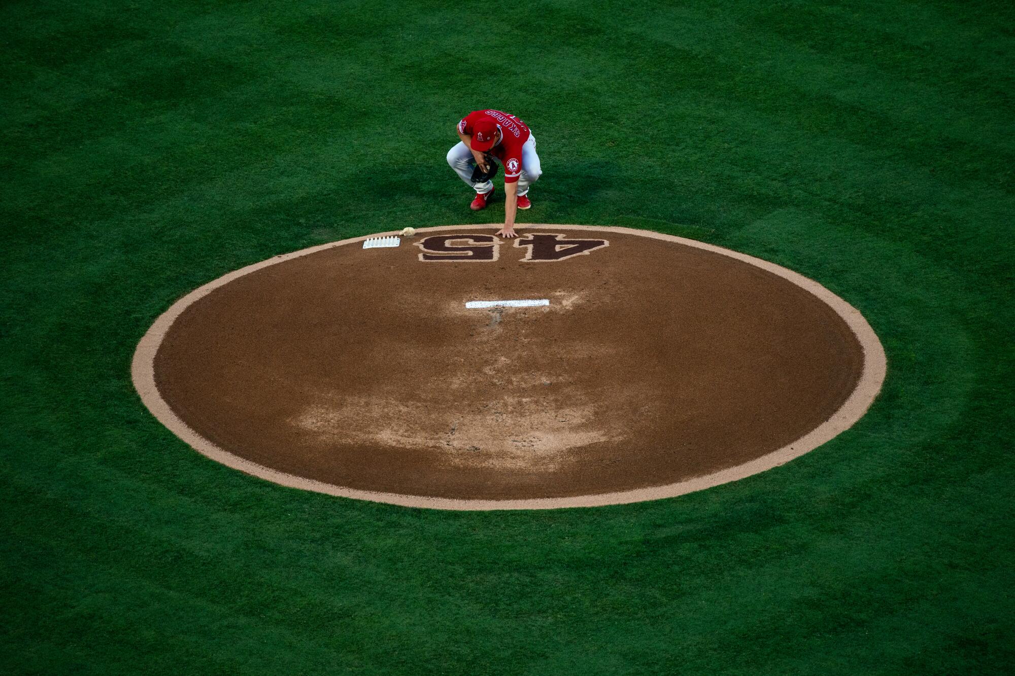 Los Angeles Angels starting pitcher Taylor Cole (67) places his hand on the No. 45 on the pitchers mound.