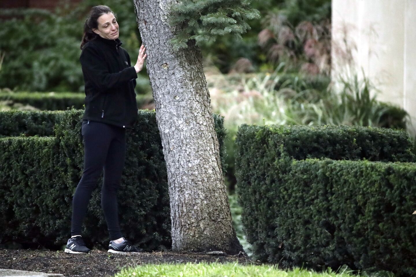 A woman touches a tree as she pauses near a memorial in front at the Tree of Life Synagogue in Pittsburgh, Monday, Oct. 29, 2018. Tree of Life shooting suspect Robert Gregory Bowers is expected to appear in federal court Monday. Authorities say he expressed hatred toward Jews during the rampage Saturday and in later comments to police.