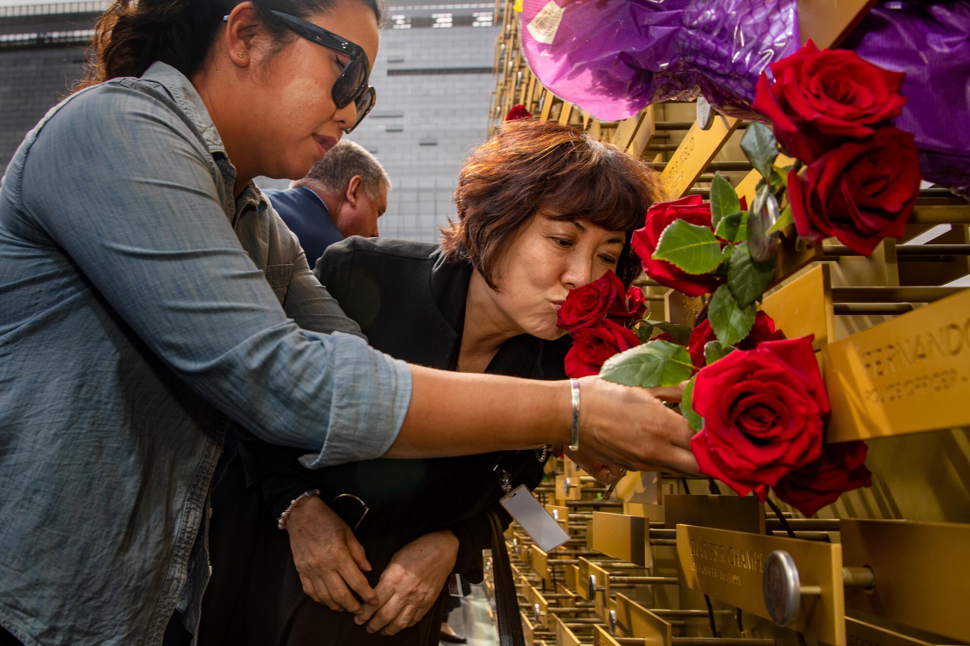  Sister Jennifer Lee, left, places a flower as mother Choung Ja Lee kisses the nameplate 