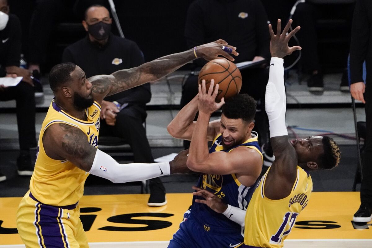 The Lakers' LeBron James, left, and Dennis Schroder trap Warriors guard Stephen Curry.