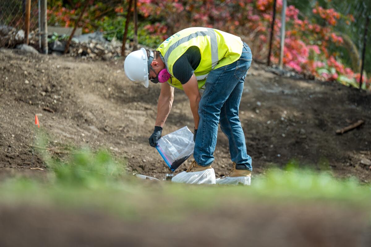Environmental unit leader Daniel Walsh pours soil samples into a jar from where a house burned in the Mountain fire