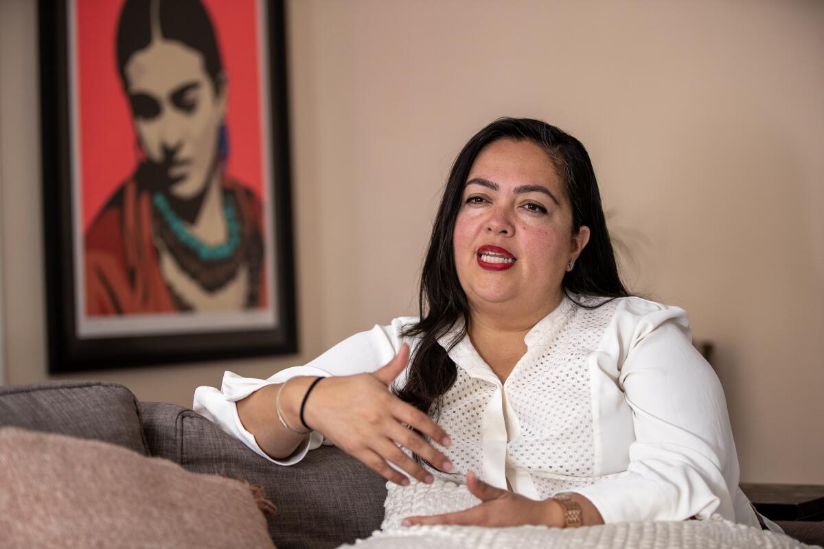 Assemblymember Wendy Carrillo sits and talks near a painting of a woman.