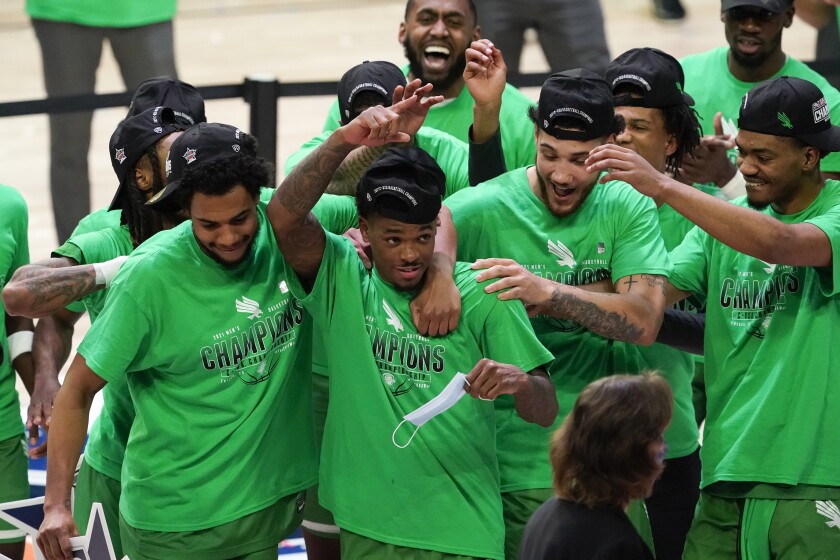 North Texas guard Javion Hamlet, center, celebrates with teammates after the championship game against Western Kentucky in the NCAA Conference USA men's basketball tournament Saturday, March 13, 2021, in Frisco, Texas. North Texas won 61-57 in overtime. (AP Photo/Tony Gutierrez)