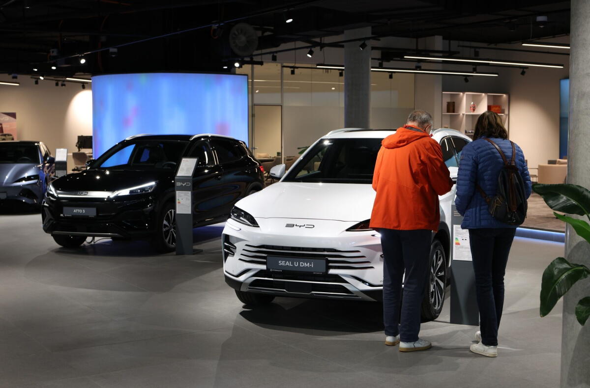 People look at a car in a showroom.