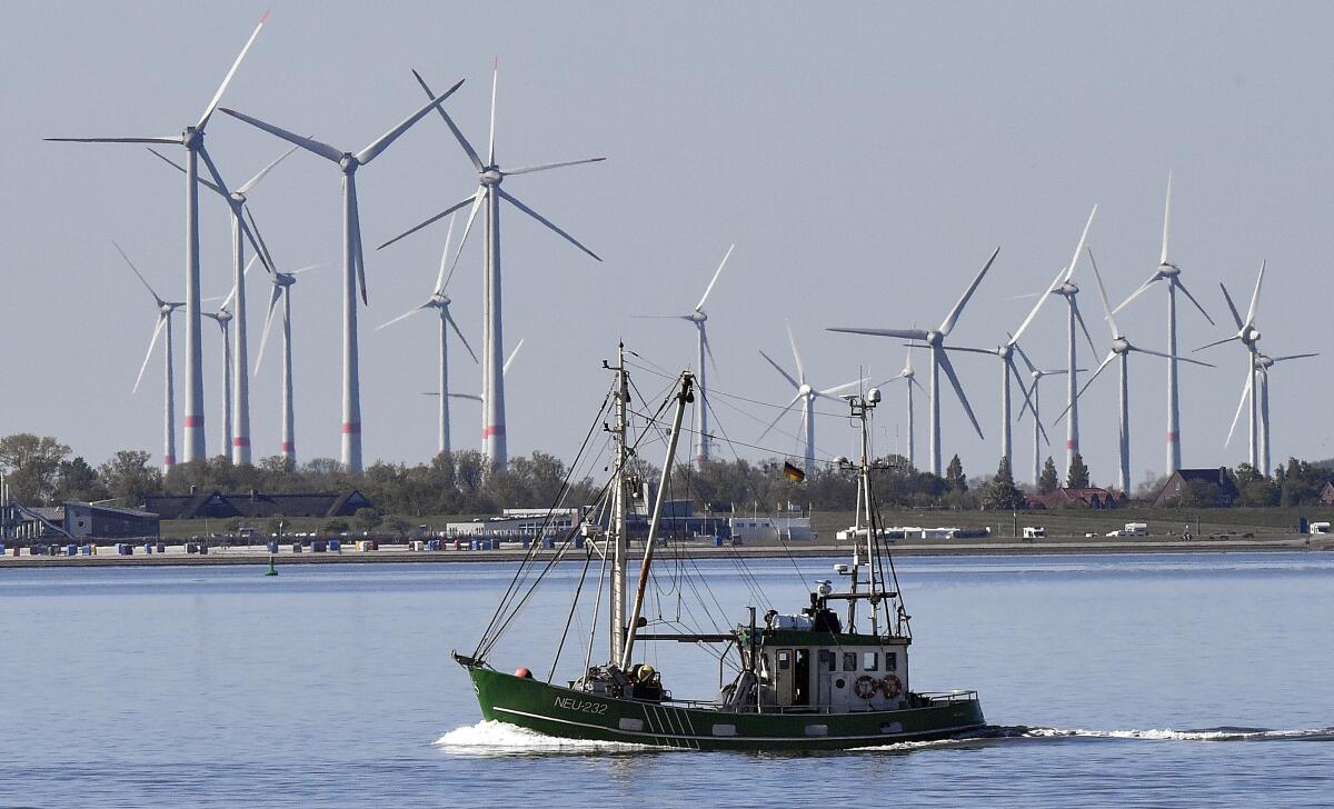 A boat with wind turbines on the shore behind