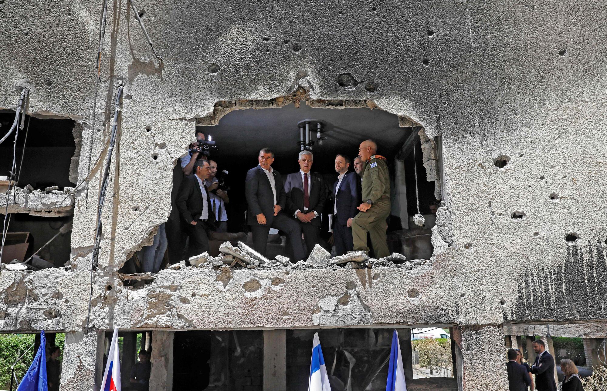 Men in suits are visible through a hole punched in a second-story wall.