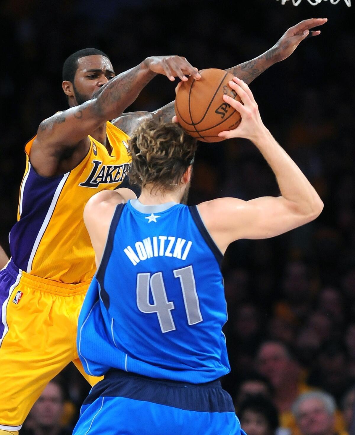 Lakers forward Earl Clark alters the shot of Dallas Mavericks forward Dirk Nowitzki.