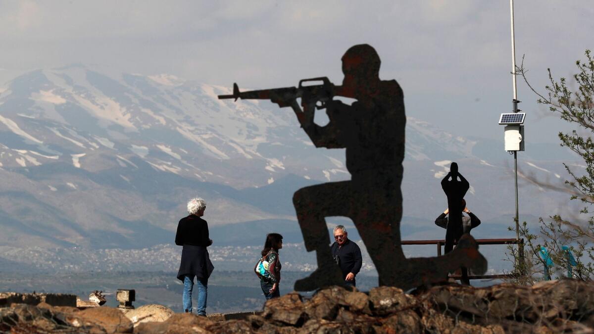 Israeli tourists stand near silhouetted cutout of an Israeli soldier at Ben Tal, next to the Israeli-Syrian border in the Golan Heights.