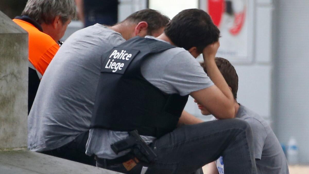 A man is comforted by officials at the scene following a shooting in Liege, Belgium, on May 29.