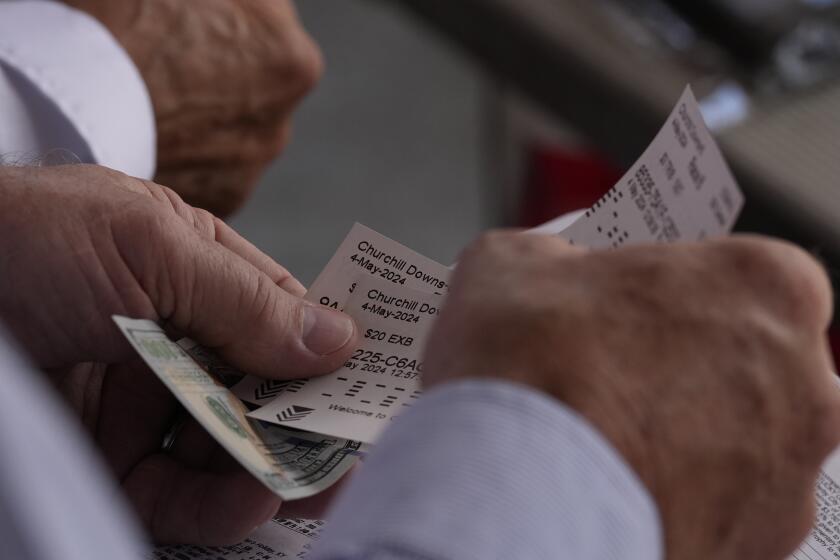 A race fan bets on horses at Churchill Downs before the 150th running of the Kentucky Derby horse race Saturday, May 4, 2024, in Louisville, Ky. (AP Photo/Brynn Anderson)