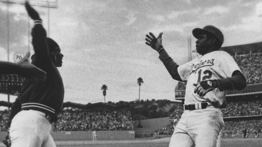 Glenn Burke, left, goes to give a high-five to teammate Dusty Baker after Baker hit a home run in 1977.