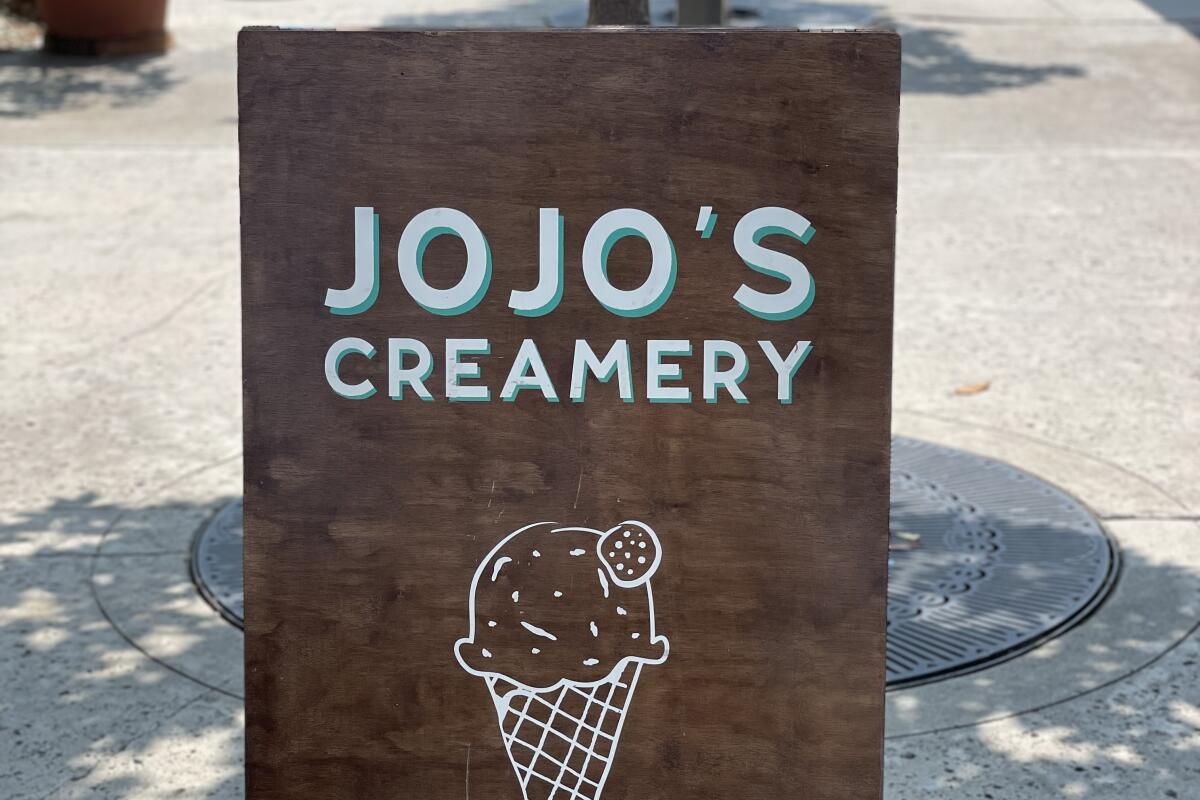 A store sign that says JoJo's Creamery and a drawing of an ice cream cone
