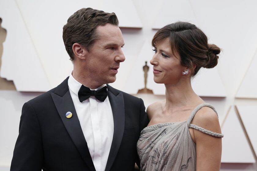 Actor Benedict Cumberbatch in a tuxedo looks toward his wife Sophie at a red-carpet event
