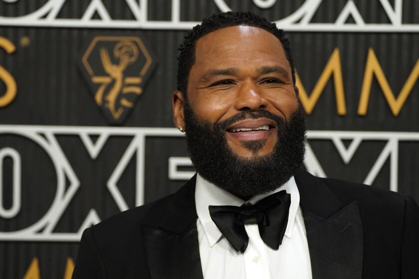 Anthony Anderson smiles while posing in a tuxedo