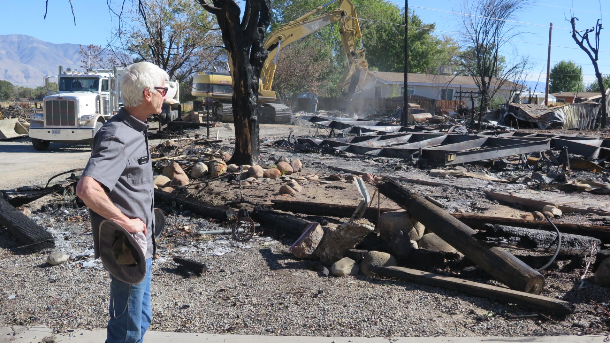 A man looks over ruins after a fire