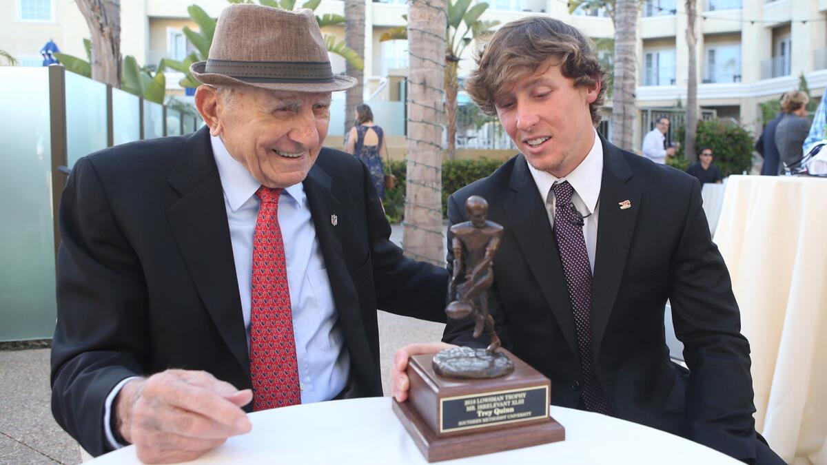 Mr. Irrelevant founder Paul Salata shares a laugh with 2018 Mr. Irrelevant Trey Quinn with the Lowsman Trophy sitting in front of them prior to the Lowsman Trophy Banquet at the Balboa Bay Resort on Monday.