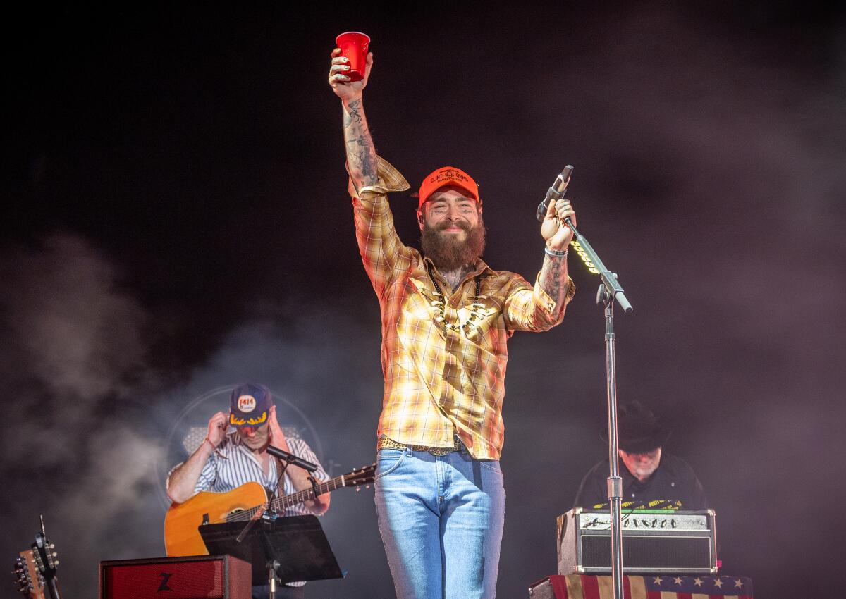 Post Malone hoists a red cup in the air as he takes the stage 