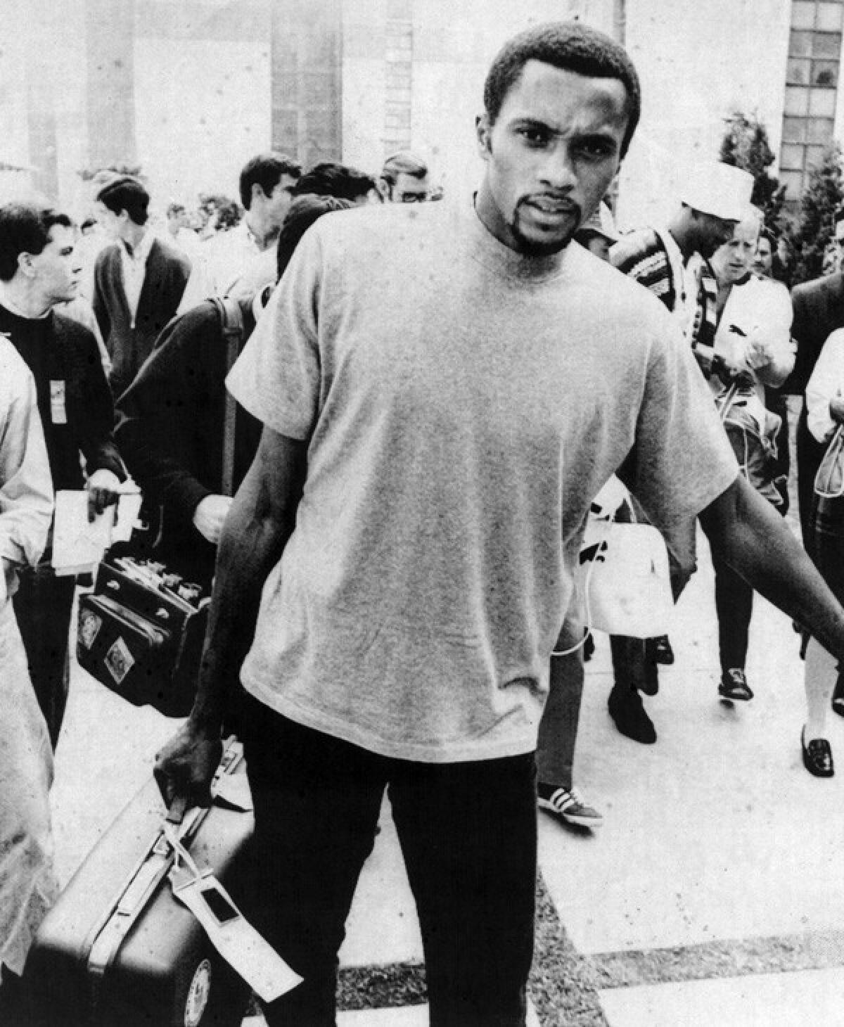 Tommie Smith carries a suitcase after being banned from the athletes village at the 1968 Olympics.