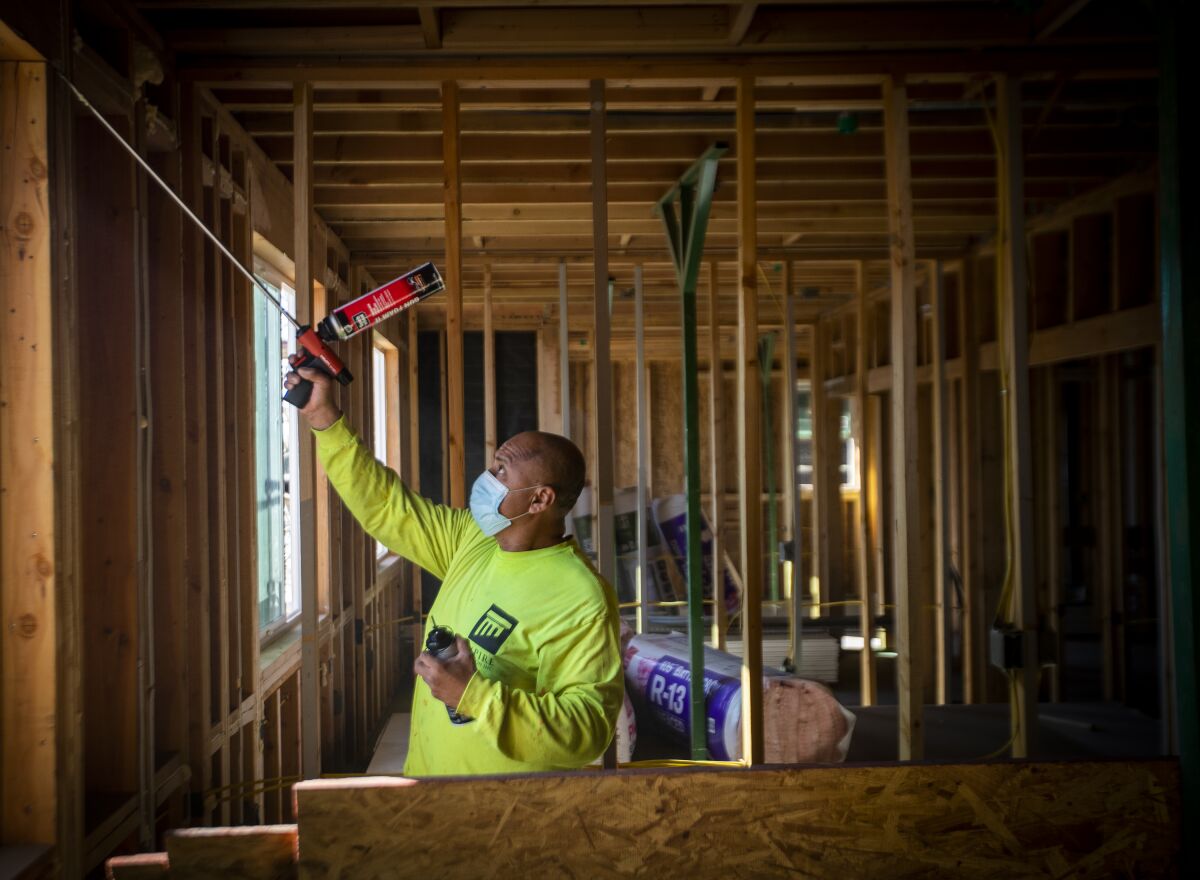 Construction worker Jose Hernandez seals windows at an all-electric housing development being built in San Bernardino.