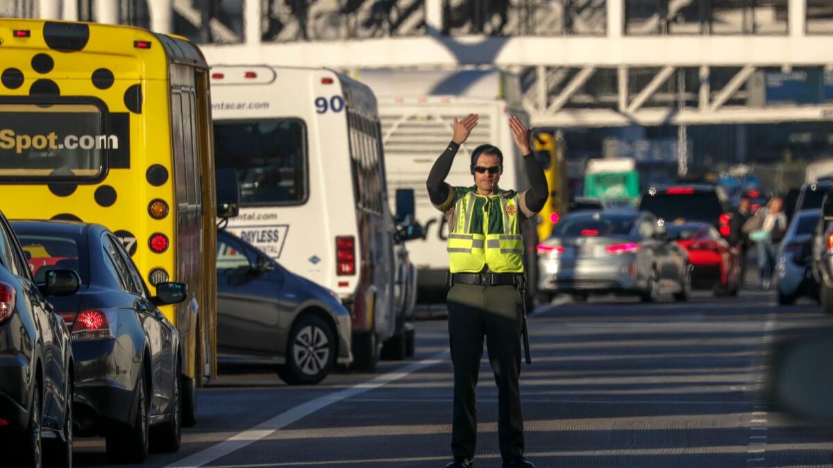 A Los Angeles airport police officer directs traffic at Los Angeles International Airport on the day before Thanksgiving last year. A study ranked LAX near the bottom when it comes to transit options, drive time and cost of getting to the airport.