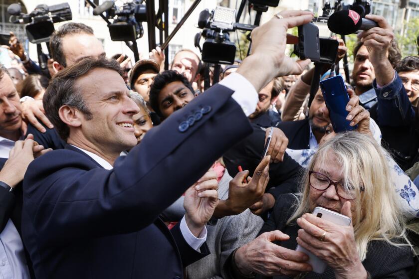 El presidente francés y candidato presidencial centrista Emmanuel Macron se toma una selfie con residentes durante una escala de campa?a el jueves 21 de abril de 2022 en Saint-Denis, en las afueras de París. (Ludovic Marin, Pool vía AP)