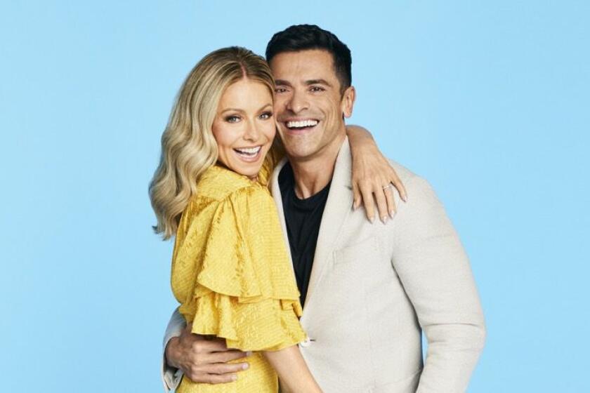 Kelly Ripa and Mark Consuelos embrace and smile. 