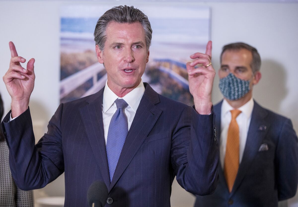 Los Angeles Mayor Eric Garcetti stands behind Gov. Gavin Newsom, listening as the governor speaks.