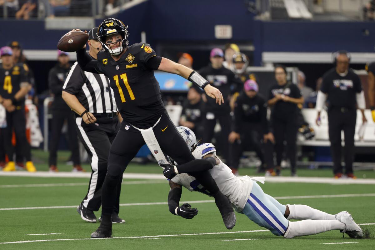 Washington Commanders quarterback Carson Wentz (11) throws a pass under pressure from Dallas Cowboys safety Donovan Wilson (6) in the second half of a NFL football game in Arlington, Texas, Sunday, Oct. 2, 2022. Wentz was penalized for intentional grounding on the play. (AP Photo/Ron Jenkins)
