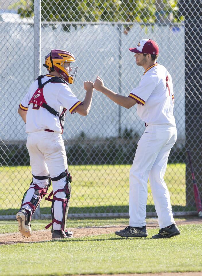 Estancia pitcher Justin Wood, right, gets a fist bump from catcher Garrett Palme in an Orange Coast League game against Costa Mesa on Wednesday.