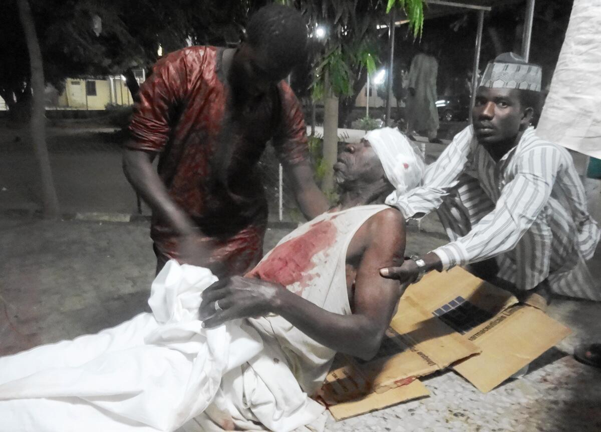 Men attend to their father in an emergency room after a suicide attack at a mosque in Kano, Nigeria, that killed more than 100 people in November 2014.