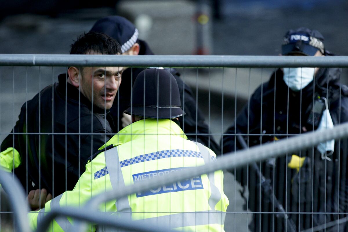 Police officers detain a man after he entered the grounds of the Houses of Parliament in London, Wednesday, Dec. 1, 2021. (AP Photo/David Cliff)