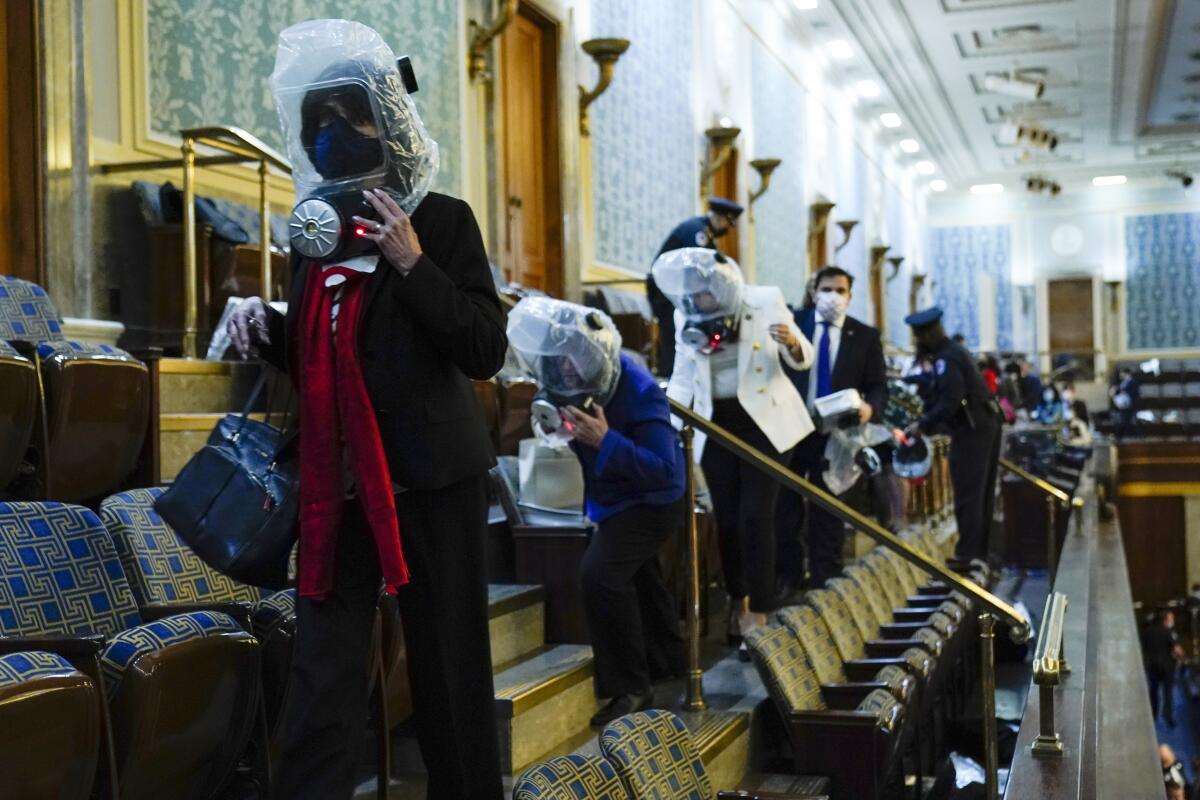 Members of Congress wear emergency gas masks as they are evacuated from the House gallery.