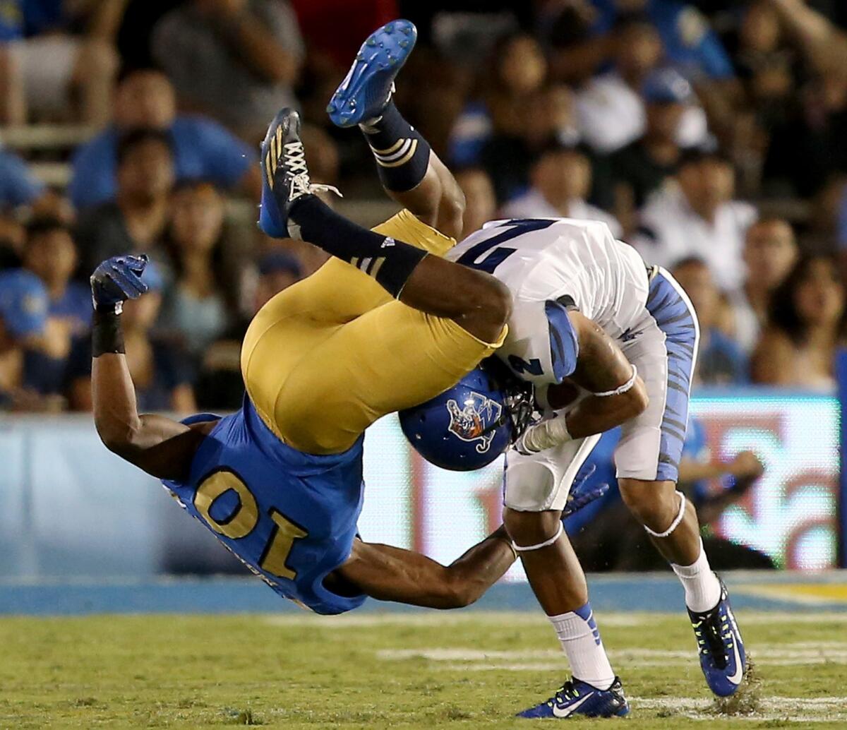 UCLA defensive back Fabian Moreau flips over Memphis receiver Joe Craig after he made a catch in the first quarter Saturday night at the Rose Bowl.