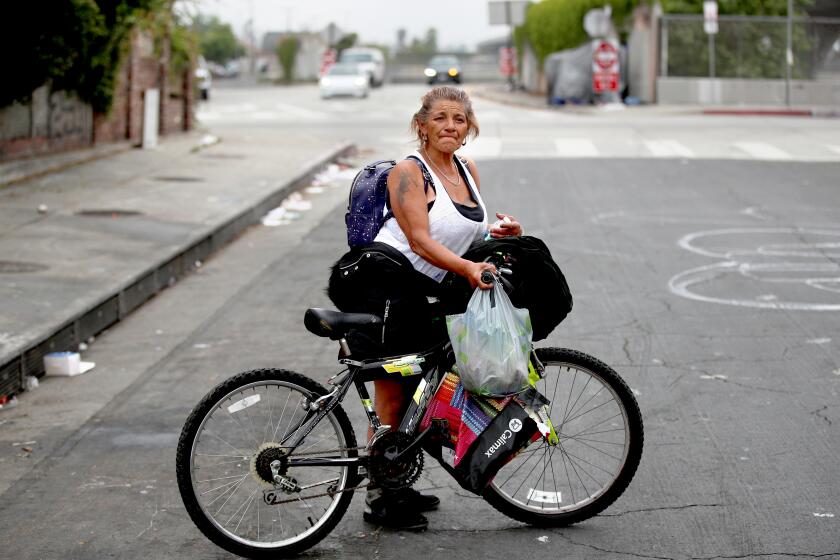 Los Angeles, CA - May 24: Beyanira Lopez, 58, who said she is staying in a hotel nearby due to the Inside Safe program, as she retrieves belongings from her and a friend's tent on a sidewalk adjacent to the 110 Freeway and a home in South Los Angeles Wednesday, May 24, 2023. Since taking office, Mayor Karen Bass has told audiences that she has found that L.A.'s unhoused will say yes when offered the chance to move inside. But in some locations, the mayor is hitting a wall - sending her Inside Safe team to encampments where not everyone has been willing to leave. Some have decided to stay put and in some locations, new homeless people have quickly arrived, putting up new tents. (Allen J. Schaben / Los Angeles Times)
