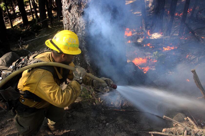 A U.S. Forest Service engine crewmember sprays down flames on the northwest flank of the August Complex, above Ruth Valley, on Sept. 22, 2020.