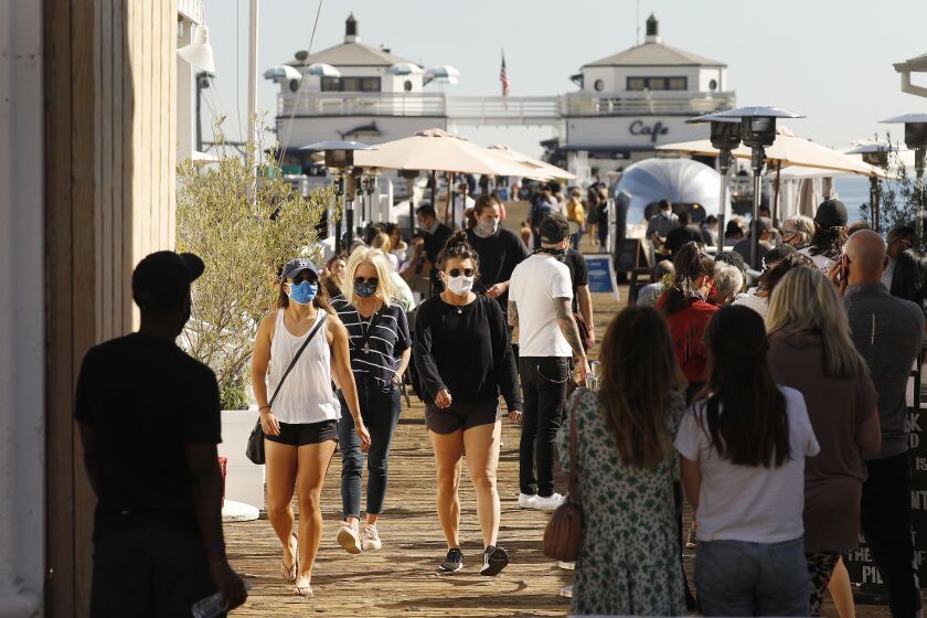 MALIBU, CA - FEBRUARY 22: People visit the Malibu Pier built in 1905 which features shops, fishing, people watching and restaurants open for outside dinning as Malibu and Playa del Rey have avoided the COVID winter surge. Malibu on Monday, Feb. 22, 2021 in Malibu, CA. (Al Seib / Los Angeles Times).