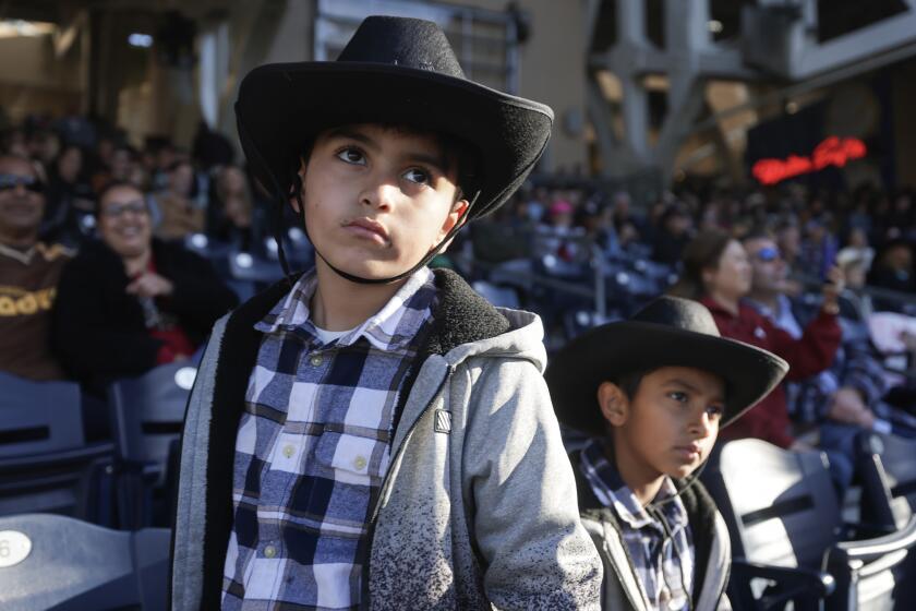 SAN DIEGO, CA - JANUARY 14, 2024: Mateo Sotero, 7, left, and his brother Issac Zamora, 8, who are from Tijuana, watch the San Diego Rodeo at Petco Park for in San Diego on Sunday, January 14, 2024.