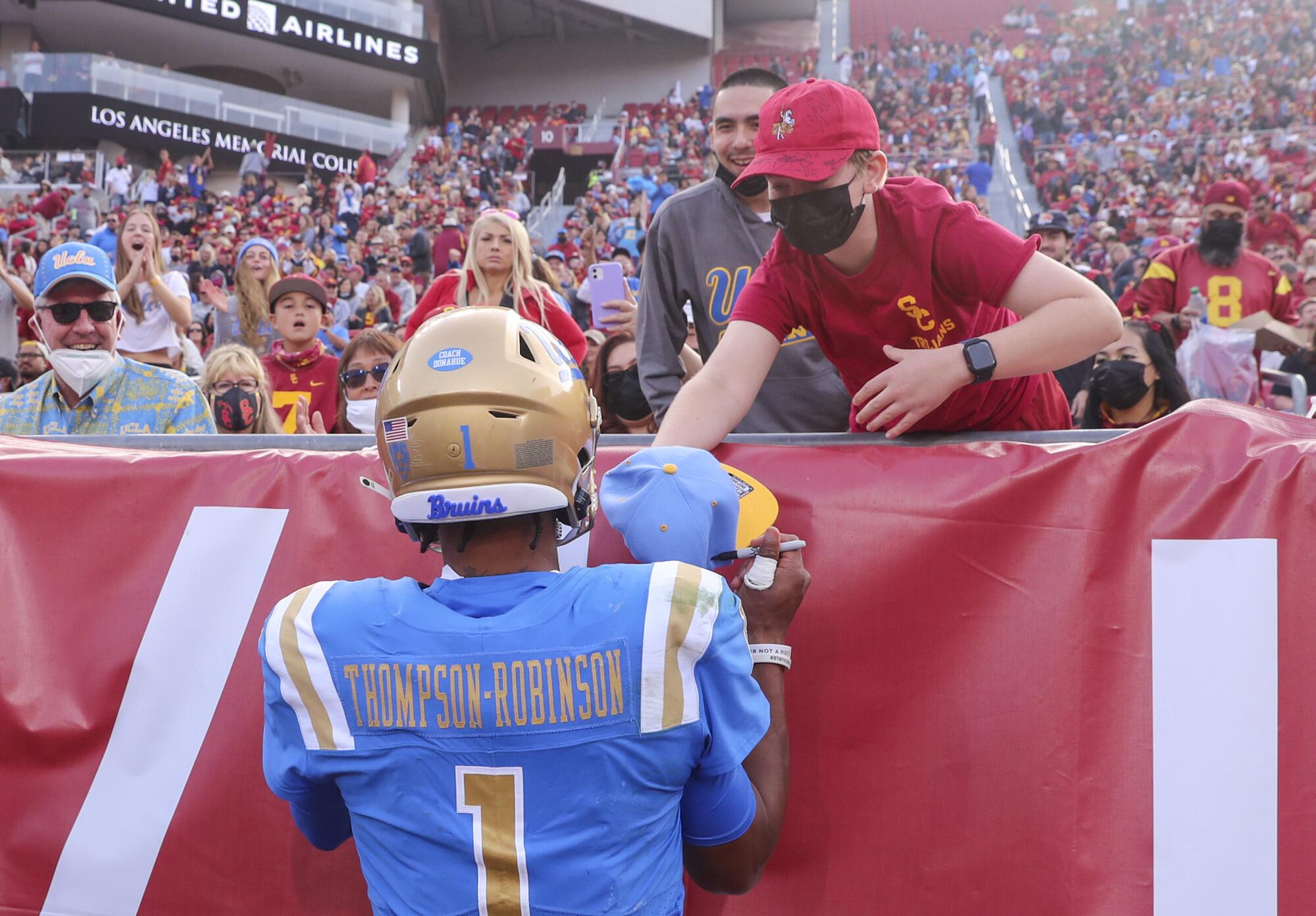 UCLA quarterback Dorian Thompson-Robinson, signs a UCLA hat for a fan.