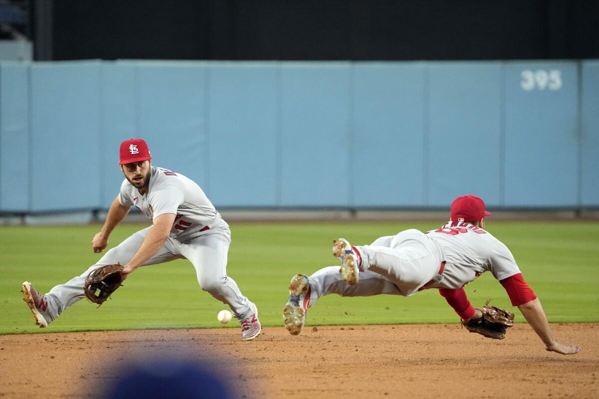 St. Louis Cardinals shortstop Paul DeJong, left, fields a ball hit by Will Smith as third baseman Nolan Arenado dives.