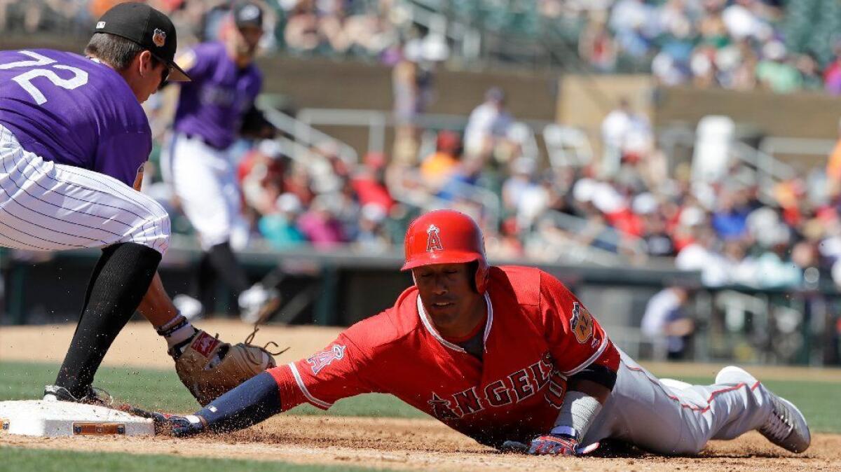 Angels' Yunel Escobar dives back to first as Rockies first baseman Jordan Patterson takes the throw during a spring training game on Mar. 16 in Scottsdale, Ariz.