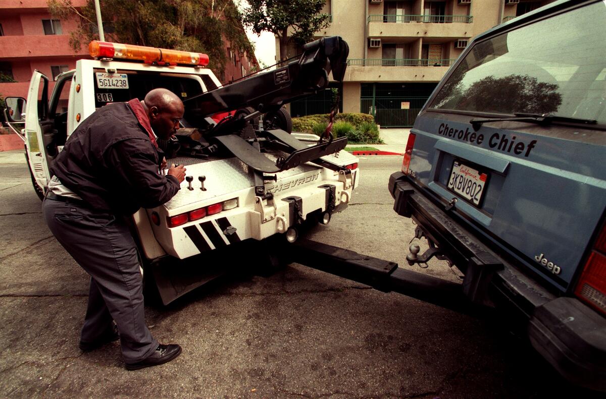 A tow truck operator hooks up a vehicle to be towed